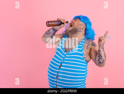 Fat man with beard and wig smokes cigarettes and drinks beer Stock Photo