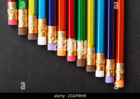 Colored pencils in a row on a black background. Free space, top view Stock Photo