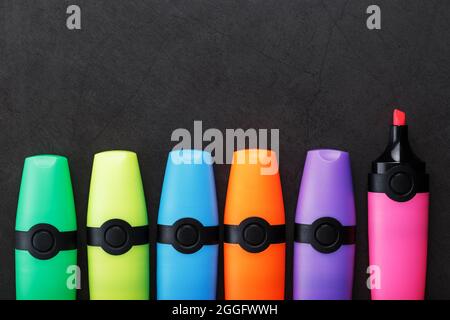 Multi-colored markers in a row on a black background, top view. The concept of creativity and study time Stock Photo
