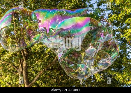 Families enjoy the street entertainment along the Southbank in London as a performer blows large bubbles across the pavement, England, United Kingdom. Stock Photo