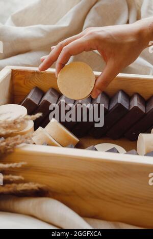 Hand take homemade soap from wooden box full of natural solid shmpoo and soaps Stock Photo