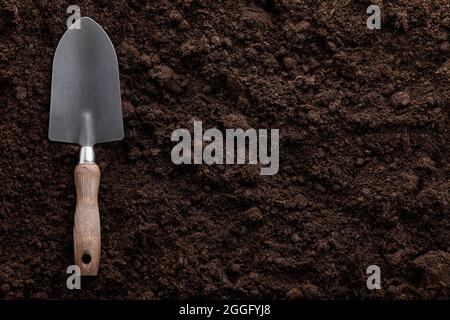Garden trowel on soil background, close up view Stock Photo