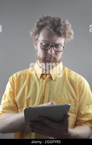 Young serious Hungarian man using his tablet against a gray background Stock Photo