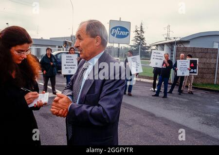 Act Up Paris Demonstration Against Pfizer Pharmaceuticals Company, Factory Closure , Medium Group HIV/AIDS Activists HOlding Protest Signs, Factory Manager being Interviewed for local media Journalist, pharma industry, teen journalist interviewing Stock Photo