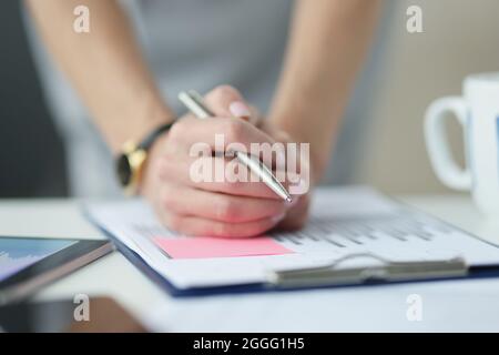 Businesswoman holding hands with ballpoint pen over documents with graphs closeup Stock Photo