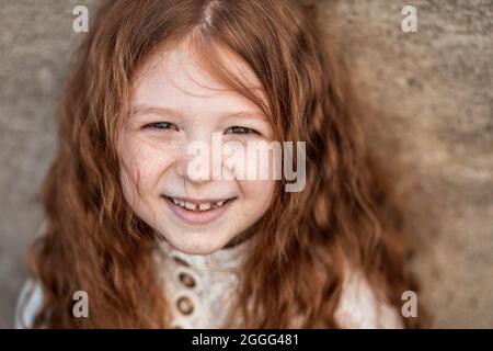 Portrait of a cute, little, freckled, ginger girl in shirt smiling