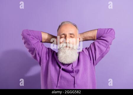 Portrait of attractive dreamy grey-haired man resting free time isolated over purple violet color background Stock Photo