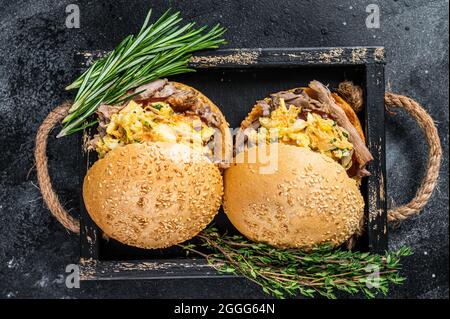 Sandwich with pulled pork meat and coleslaw salad. Black background. Top view Stock Photo