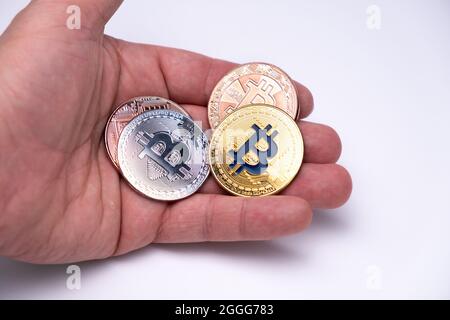 Lots of Bitcoins different colours on one hand palm. Cryptocurrency concept, bitcoin BTC standing on mens hand. Cryptocurrency lies on the palm hand. Stock Photo