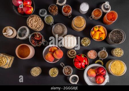 Top view of a lot of glass jars filled with all kinds of spices and fruits on black background Stock Photo