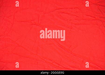 Genuine leather with wrinkles and folds, dyed in bright red. Background, pattern, texture. Stock Photo