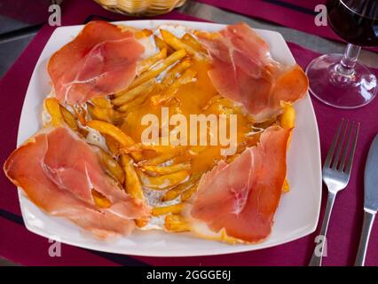 Fried eggs with fried potatoes and sliced cured ham Stock Photo