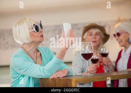Three senior happy ladies having good time and drinking wine Stock Photo