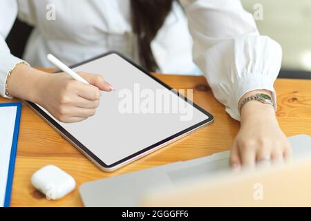 Cropped image of businesswoman using digital tablet with stylus pen on worktable, tablet blank screen mockup, designer sketching design on graphic tab Stock Photo