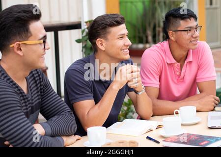 three latin students looking at the same place and smiling Stock Photo