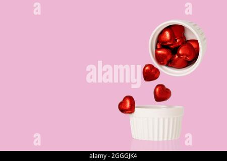 Heart shaped chocolate candies falling from a ceramic cup. Levitation food photography. Stock Photo