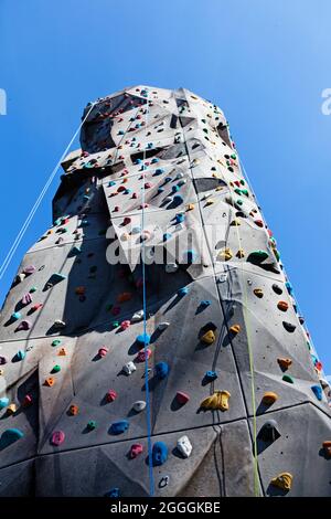 high climbing wall with ropes and various ledges Stock Photo