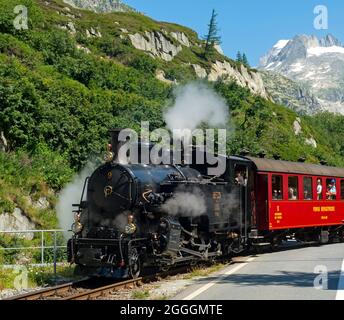 Furka Cogwheel Steam Railway crossing the Furka Pass mountain road, Furka region, Valais, Switzerland Stock Photo