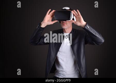 Man in leather jacket interacting with vr glasses black background Stock Photo