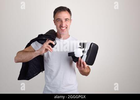 Man showing virtual reality headset dressed in white t-shirt on white isolated background Stock Photo