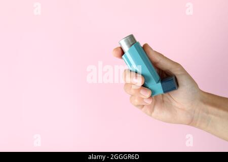 Female hand holds asthma inhaler on pink background Stock Photo