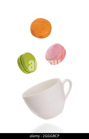 Colorful macaroons levitating on a white tea cup. Isolation on white background. Stock Photo