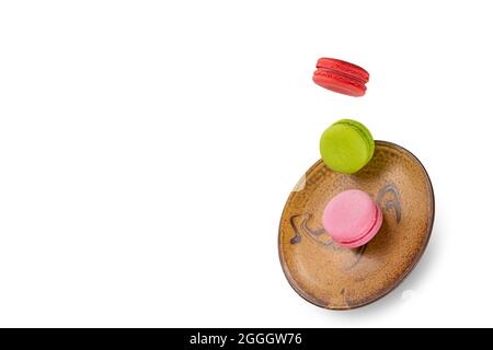 Colorful macaroons levitating on an orange plate.  Levitation food photography concept. Stock Photo