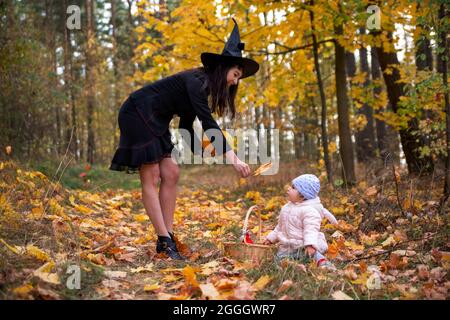 black witch woman with little toddler bunny in the autumn forest. halloween celebration, costume party. Stock Photo