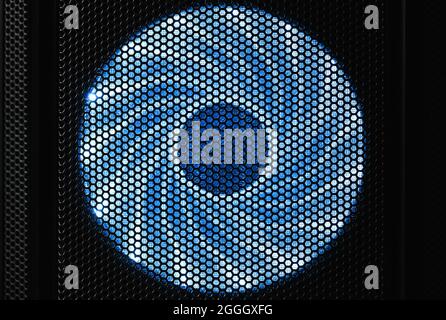 Illuminated by blue LED lights PC cooler fan in dark desktop case, front view Stock Photo