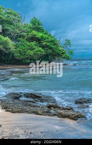 Beautiful coastline of Pacific Costa Rica. Rocks on the foreground and tropical vegetation on the background. Before the sunset. Stock Photo