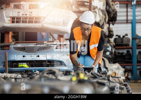 Portrait of Black African American woman holding tablet check and work in factory of old auto spare parts Stock Photo