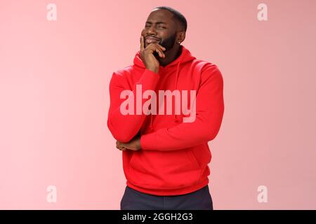 Doubtful sceptical young african-american hesitant bearded guy frowning sarcastic unsure touching chin thoughtful having bad feeling about idea, look Stock Photo