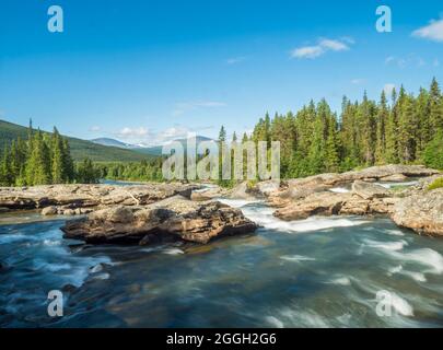Beautiful landscape with long exposure water stream and cascade of river Kamajokk, boulders and spruce tree forest in Kvikkjokk village in Swedish Stock Photo