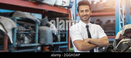 Portrait of man crossing arm and smiled in factory of old auto spare parts Stock Photo
