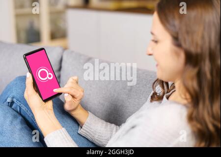 Kyiv, Ukraine - April 2, 2021: Google Fuchsia OS logo on the mobile phone screen. A woman is holding smartphone with Fuchsia logo on the display, operating system developed by Google Corporation Stock Photo