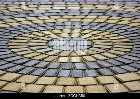 Sidewalk made of two-tone paving slabs. Pattern of concentric circles. Side view, at angle. Close-up. Selective focus. Stock Photo