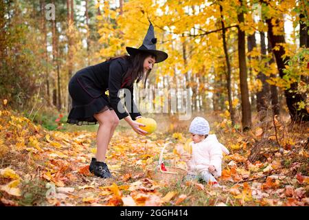 black witch woman with little toddler bunny in the autumn forest. halloween celebration, costume party. Stock Photo