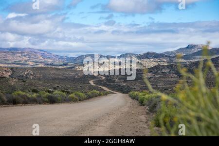 Landscape of a dirt road leading through the Kamiesburg mountains with a cloudy sky Stock Photo