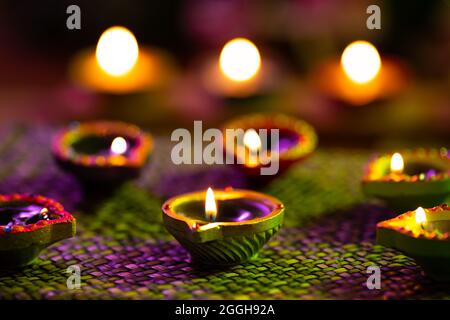 Lit candles in small decorative clay pots burning on woven table cloth Stock Photo