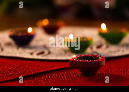 Four lit candles in small decorative clay pots burning on wooden table top Stock Photo