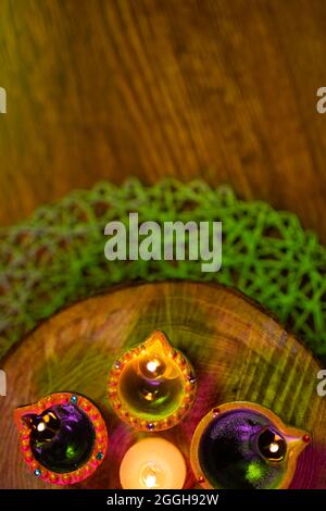 Lit candles in small decorative clay pots and tea light candle burning on round wooden board Stock Photo