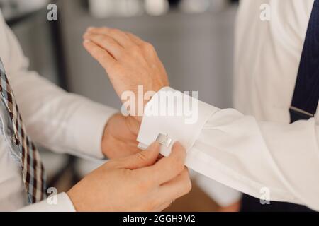 Wedding day of young man, button up cufflinks on white shirt. Elegance and business style concept. Stock Photo