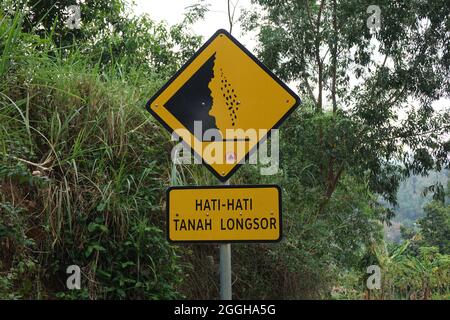 Yellow sign with a natural background. Hati-hati tanah longsor means beware of landslides Stock Photo