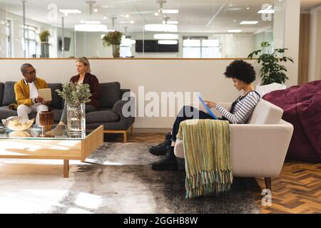 Diverse male and female colleagues working together in workplace lounge area Stock Photo