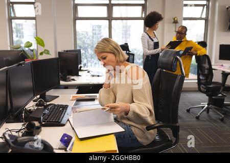 Caucasian female creative at work, sitting at desk, taking notes Stock Photo