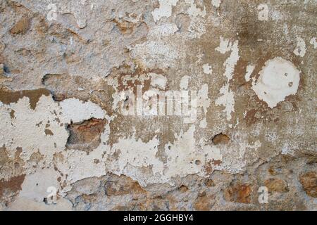 Old traditional limewashed stone wall with peeling plaster, white rustic background Stock Photo