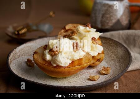 Delisious dessert. Grilled pears with cream and nuts. Coffee and honey on wooden background Stock Photo