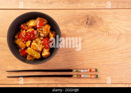 chess chicken in black bowl on wooden background - chinese food. Stock Photo