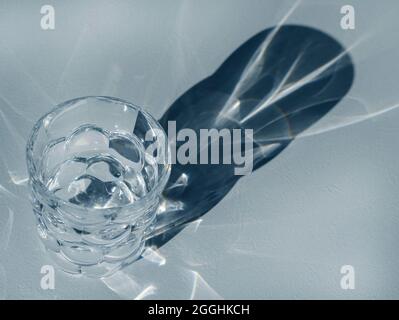 Empty glasse on grained background with hard shadows and sun glare. The reflection of the light of the glass Stock Photo