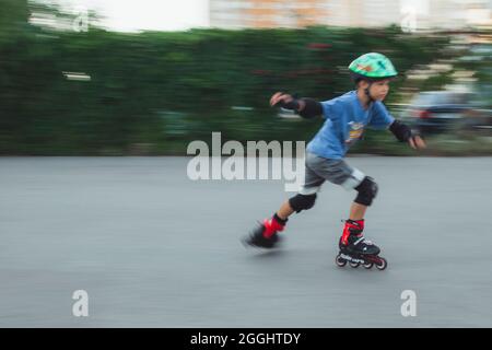 Ukraine, Kyiv - 20 June 2021: Boy training for inline skates. Rollerblade Inline Skates, Author Helmet, Powerslide Protection . Editorial Stock Photo